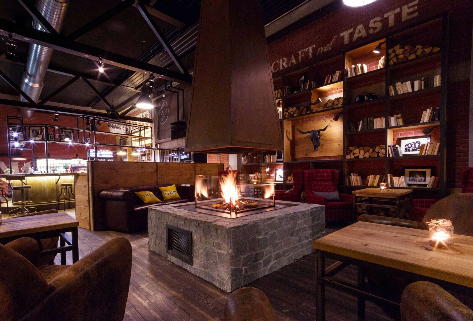 Hangulatos szoba kandallóval, fabútorokkal és könyvespolcokkal.