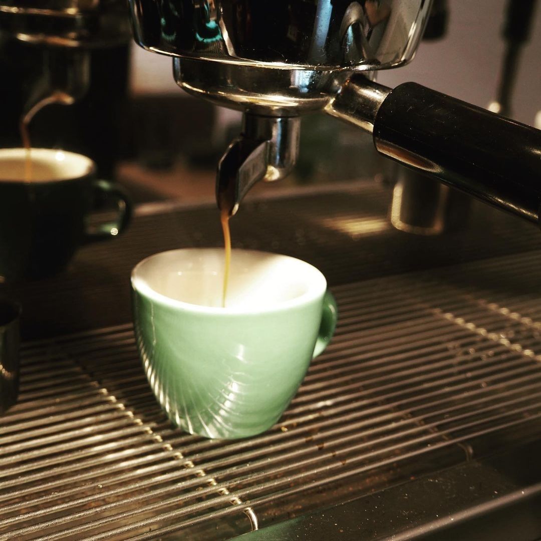 Az eszpresszógép egy zöld csészét tölt meg kávéval.