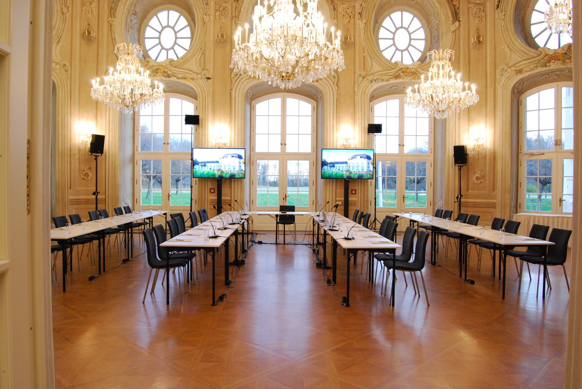 Elegáns konferenciaterem csillárokkal és nagy ablakokkal.