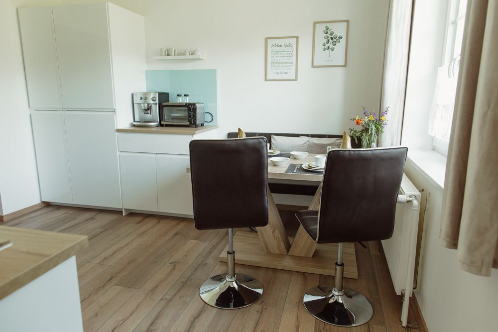 Modern konyha étkezőasztallal, székekkel és készülékekkel.