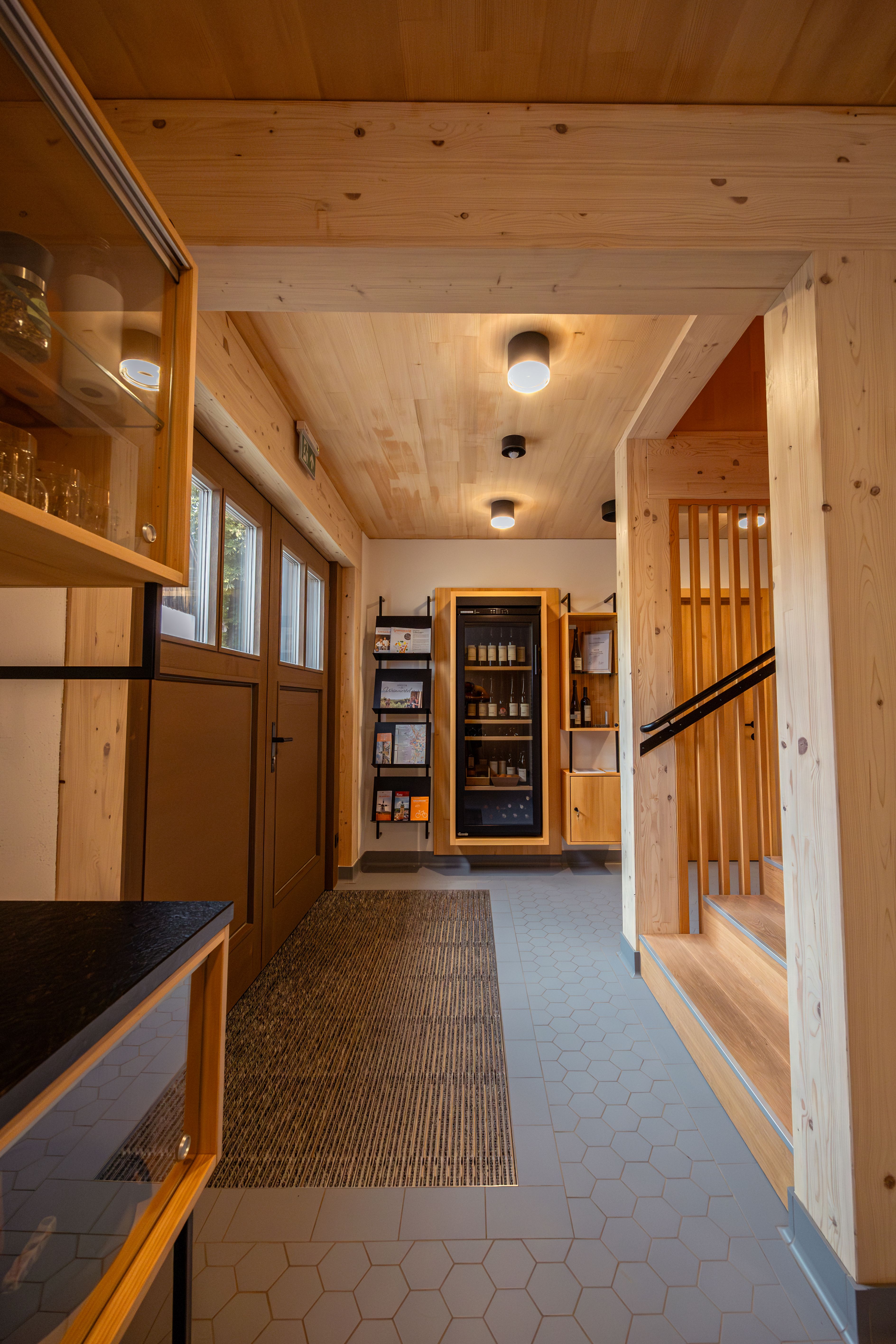 Egy modern pince a Weinviertelben alkonyatkor, szőlővel és kerttel körülvéve. Egy tábla jelzi: "Nyaralás egy tanyán".