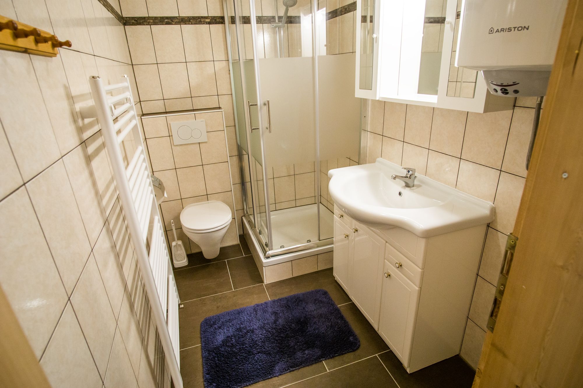 Fürdőszoba zuhanyzóval, mosdóval, WC-vel és törölközőradiátorral.