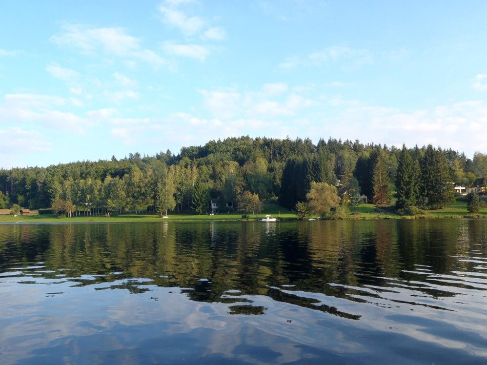 Kilátás a Thurnberg víztározóra, erdős parttal és tiszta égbolttal.
