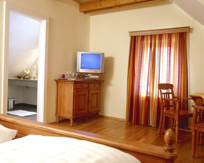 Hangulatos szoba fabútorokkal, TV-vel és színes függönyökkel.