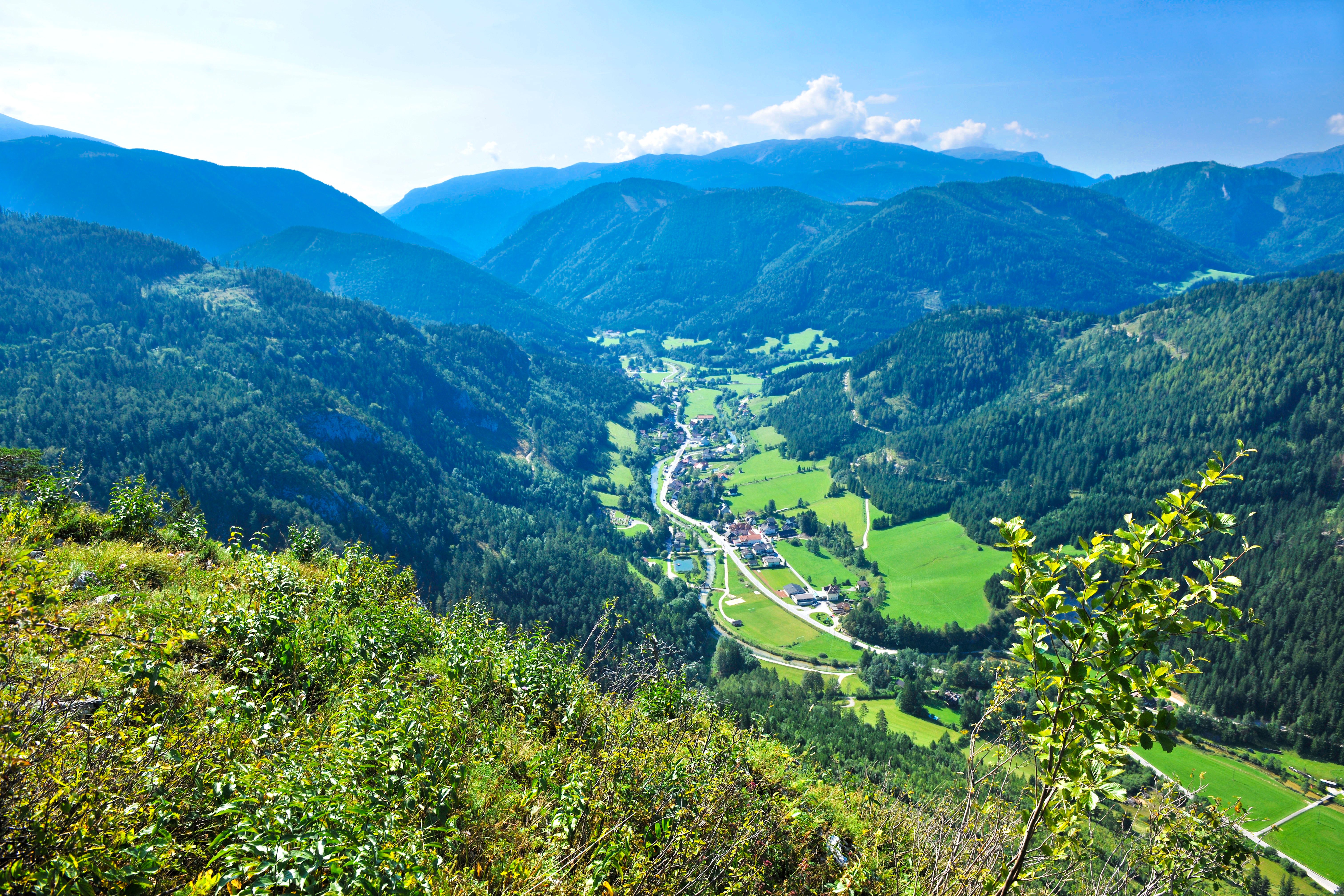 Panorámakép egy zöld völgyre, a háttérben hegyekkel.
