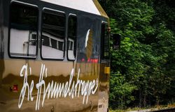 Die goldene Bahn schmiegt sich sanft in die umgebende Natur, während die Bäume im Hintergrund ein Gefühl von Ruhe und Abgeschiedenheit vermitteln. Hier, wo die Himmelstreppe die Landschaft durchquert, wird jeder Moment zu einem unvergesslichen Erlebnis in der malerischen Umgebung des Mostviertels.