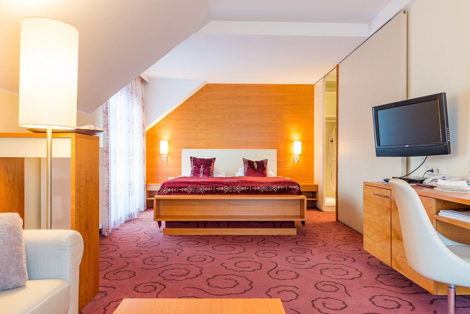 Hotelszoba franciaággyal, íróasztallal és televízióval.