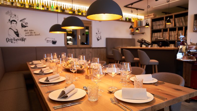 Eleganter, gedeckter Tisch in einem stilvollen Restaurant mit warmem Licht und moderner Dekoration.