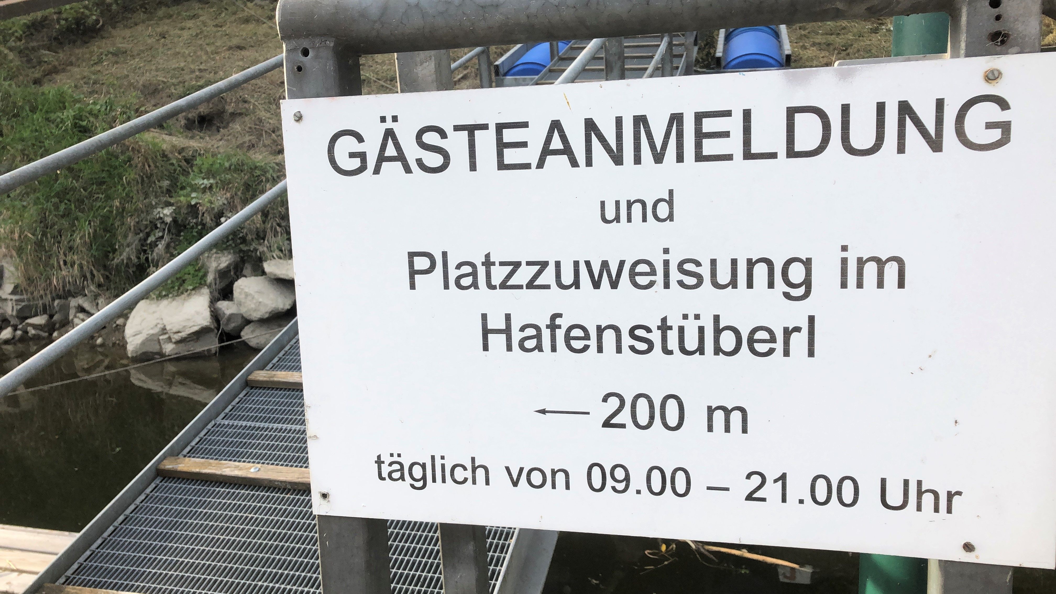 "Vendégregisztráció és helykiosztás a kikötői étteremben, 200 m, naponta 09.00-21.00 óra között" feliratú tábla.