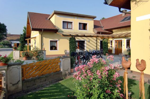 Sárga ház kerttel és kerékpárokkal az ajtó előtt.