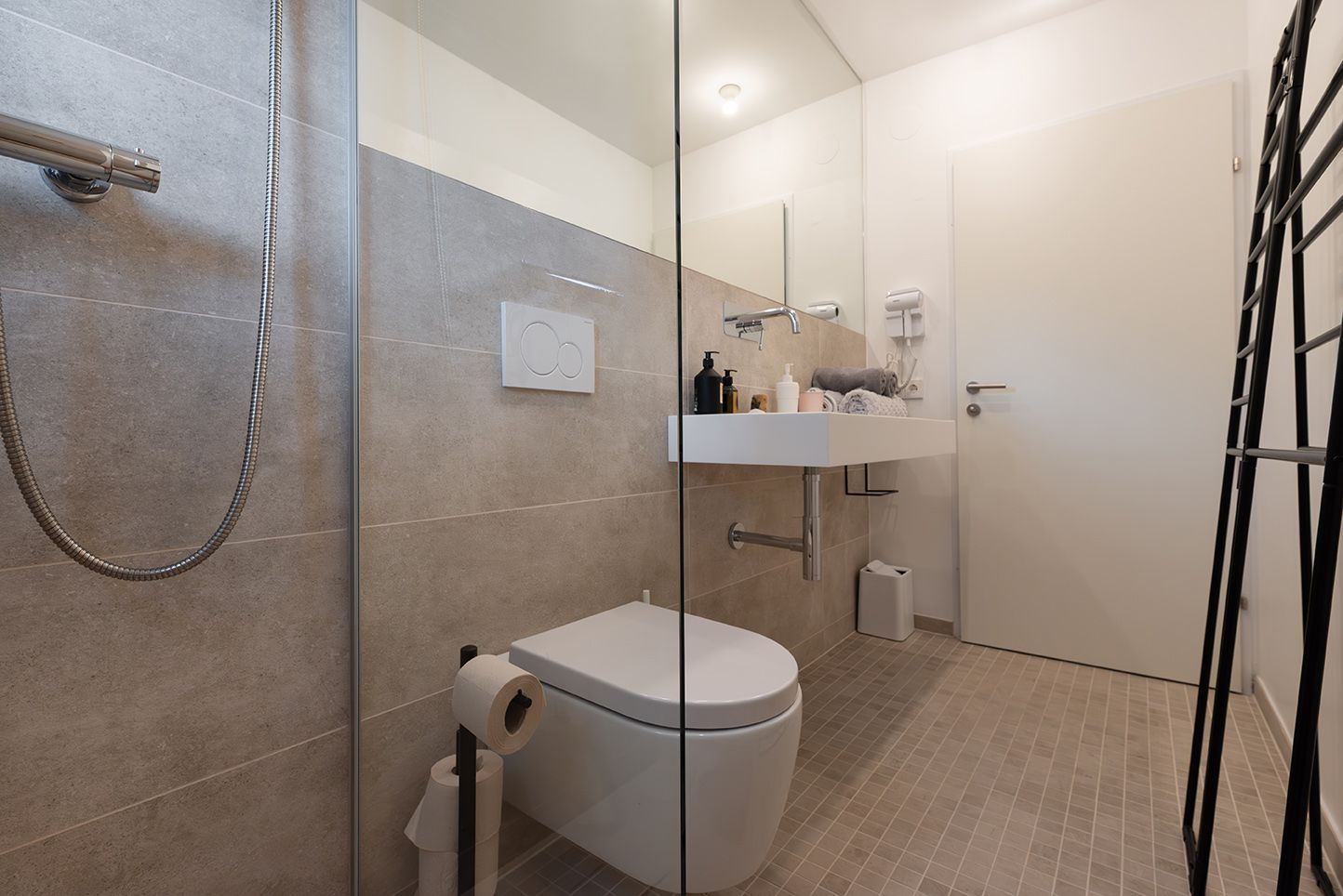 Modern fürdőszoba üvegzuhannyal, mosdóval és WC-vel.