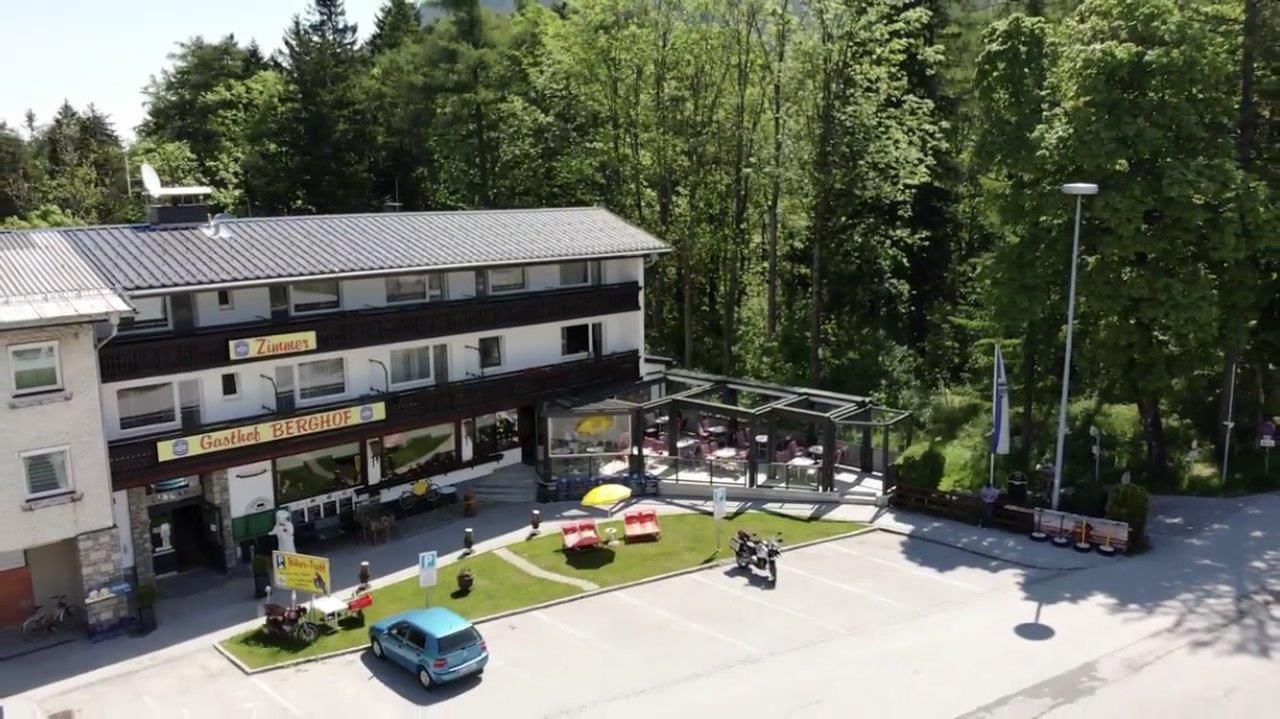 A Gasthof Berghof külső nézete, terasz és parkoló, fákkal körülvéve.