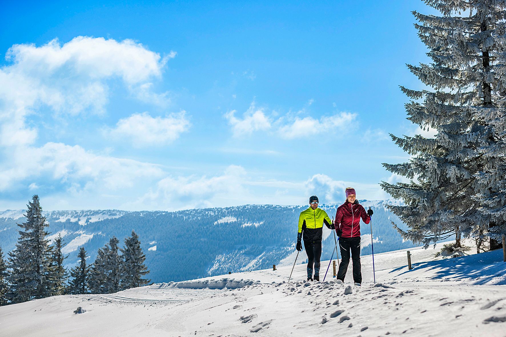 Két sífutó egy hóval borított pályán egy téli hegyvidéki tájban.