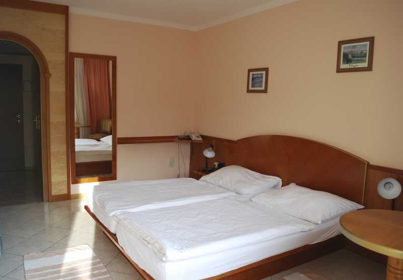 Hotelszoba franciaággyal, éjjeli lámpákkal és falfestményekkel.