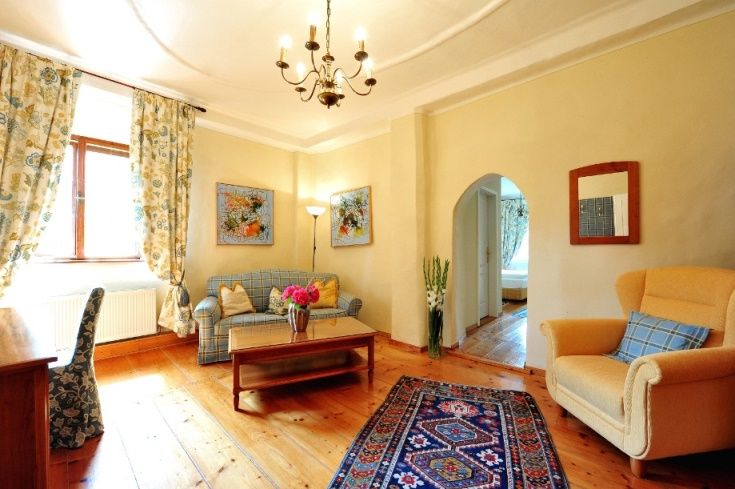 Hangulatos nappali fapadlóval, kanapéval, karosszékkel, szőnyeggel és virágokkal.