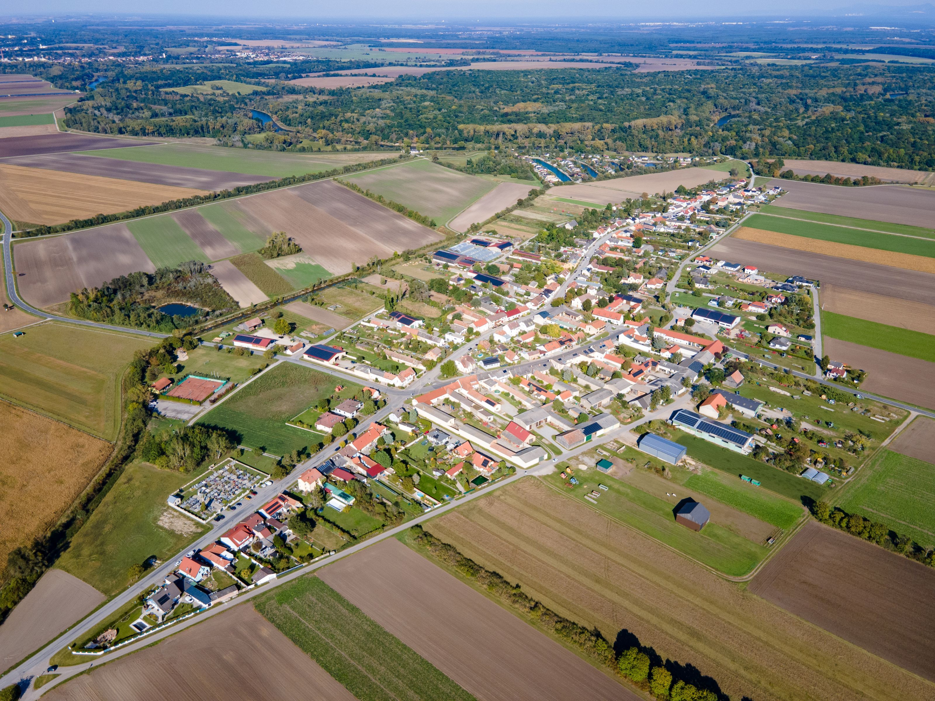 Weiden an der March település légi felvétele, mezőkkel, lakóházakkal és a háttérben a folyó medrével.