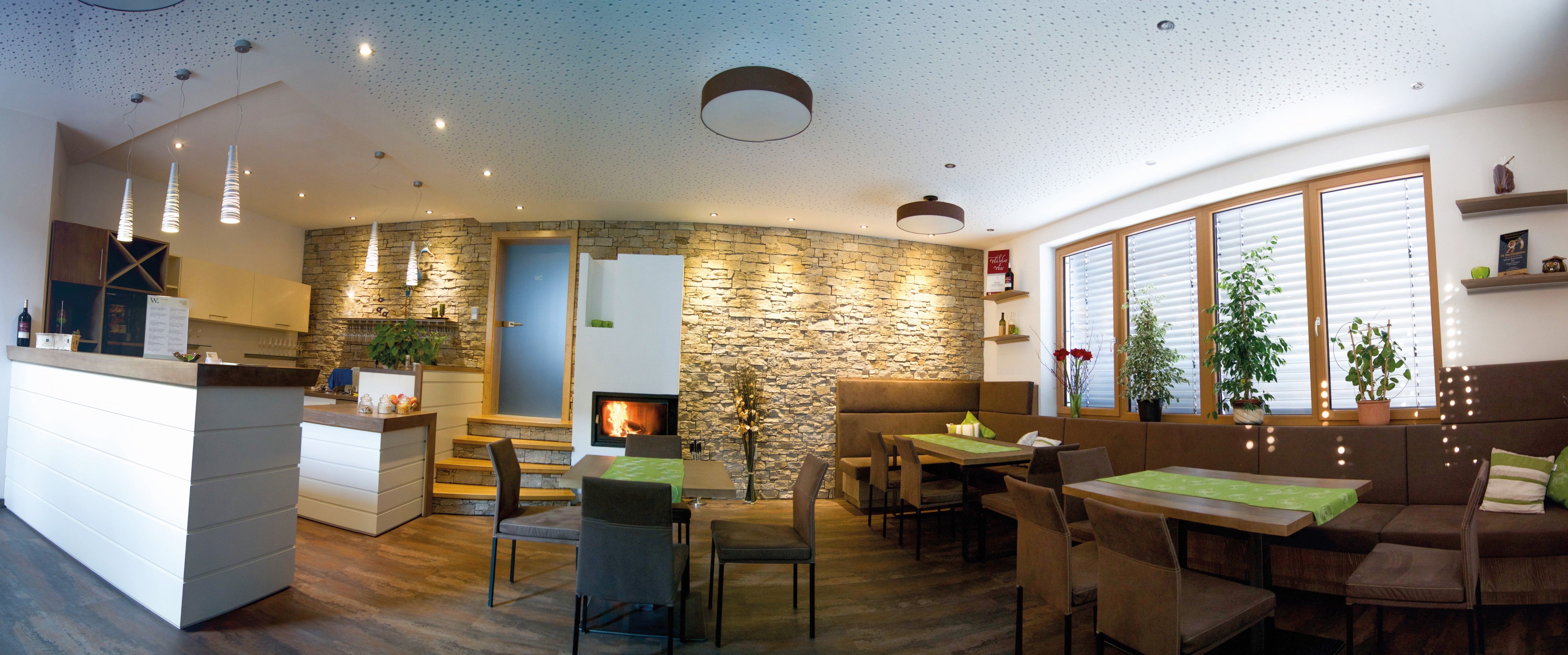 Modern kóstolóterem fabútorokkal, kőfallal, kandallóval és növényekkel.