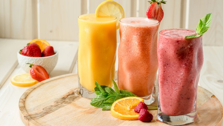 H&aacute;rom smoothie poh&aacute;rban, f&aacute;b&oacute;l k&eacute;sz&uuml;lt deszk&aacute;n, gy&uuml;m&ouml;lcs&ouml;kkel &eacute;s ment&aacute;val d&iacute;sz&iacute;tve.