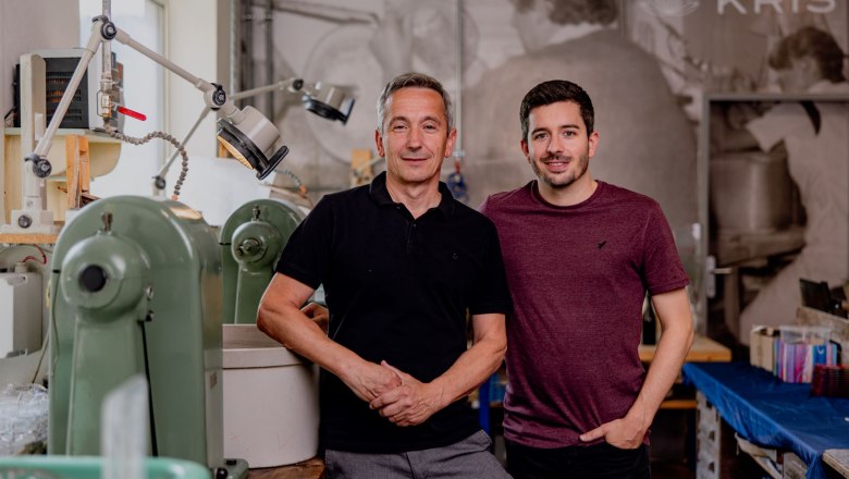 K&eacute;t f&eacute;rfi &aacute;ll egy műhelyben, a h&aacute;tt&eacute;rben g&eacute;pekkel.