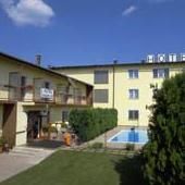 Egy sárga szálloda külső nézete medencével és kerttel.