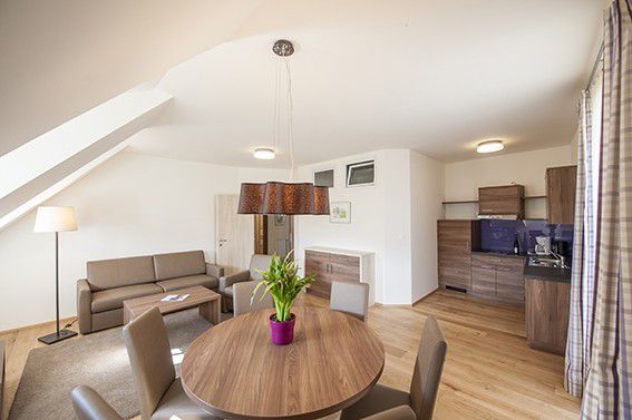 Modern nappali étkezővel, kanapéval és konyhasarokkal.