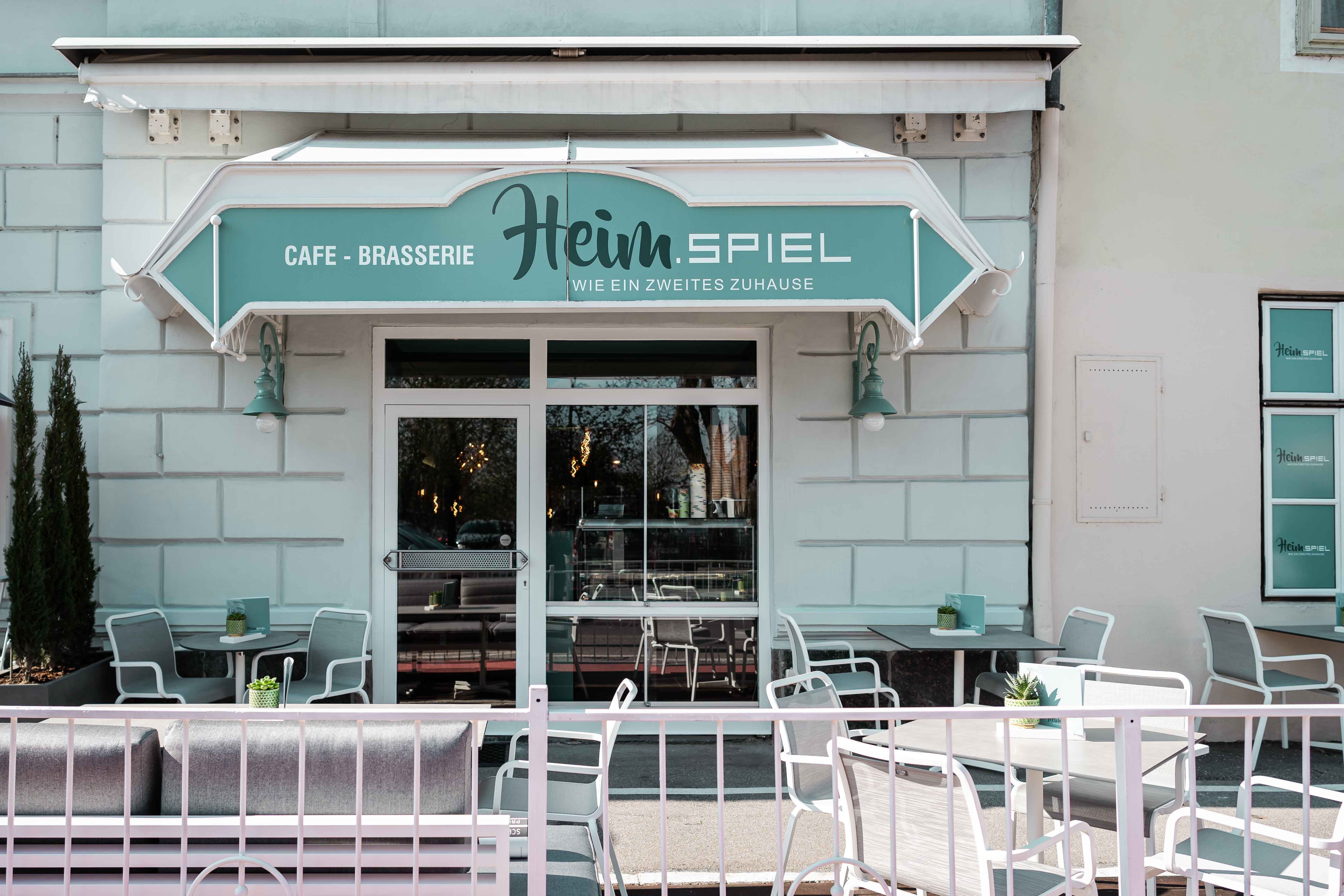 Egy kávézó külső nézete terasszal és ülőhelyekkel.