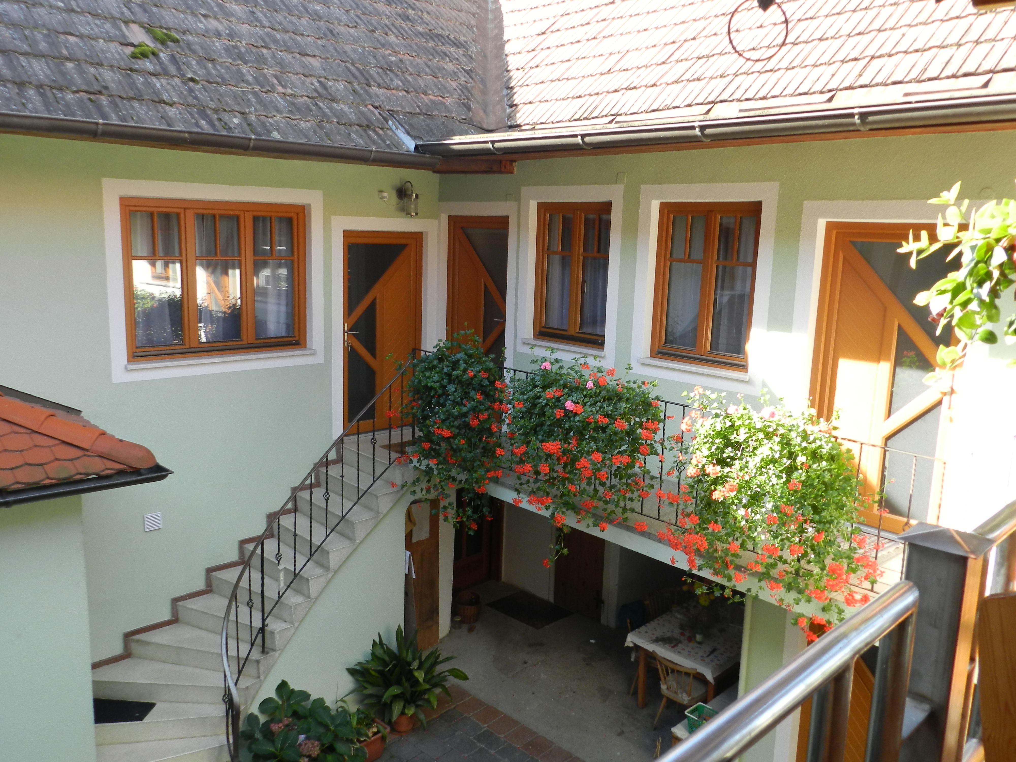 Belső udvar lépcsővel, virágokkal és asztallal.