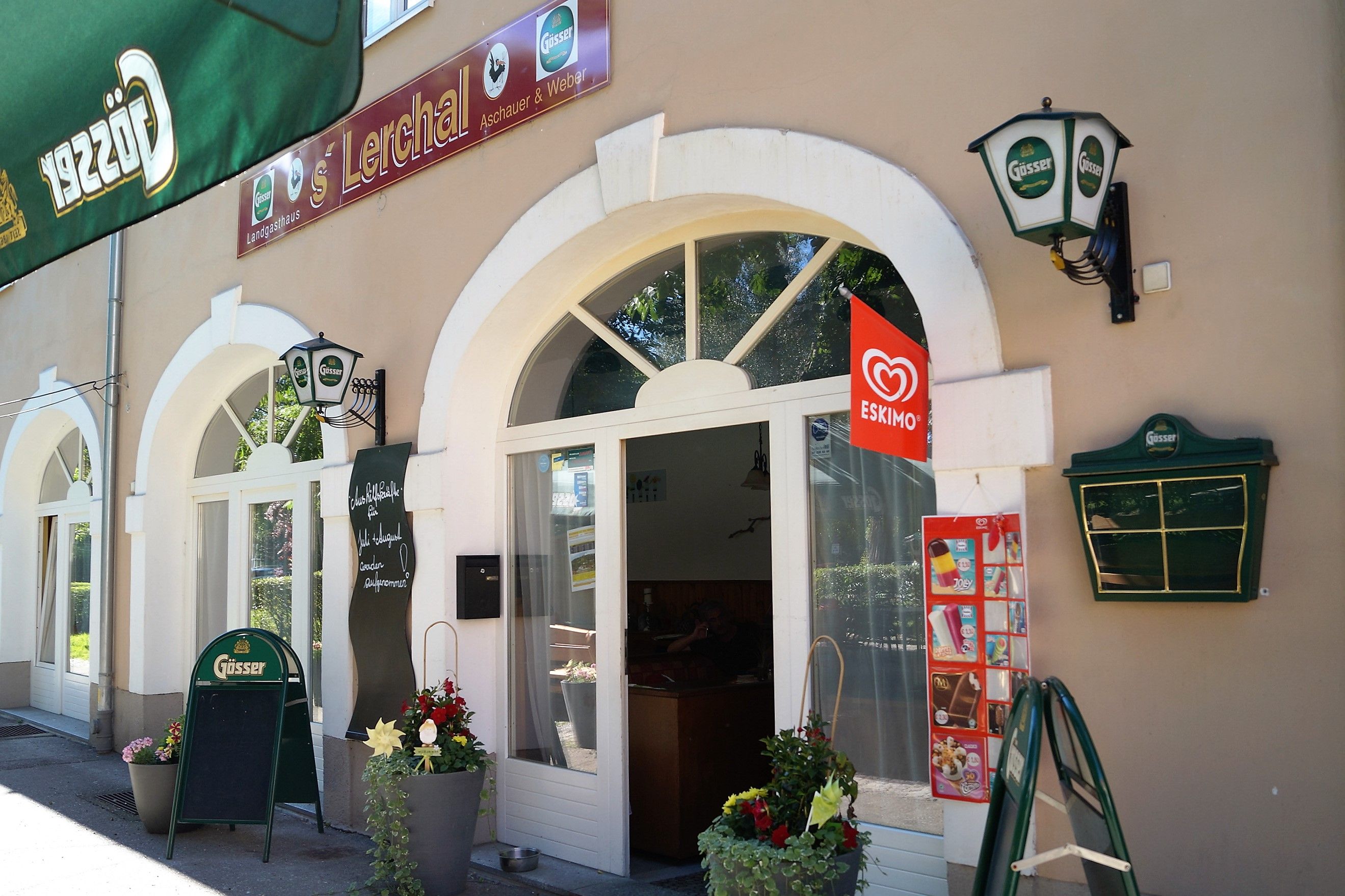 Egy étterem külső nézete Gösser feliratokkal és eszkimó fagylaltreklámmal.