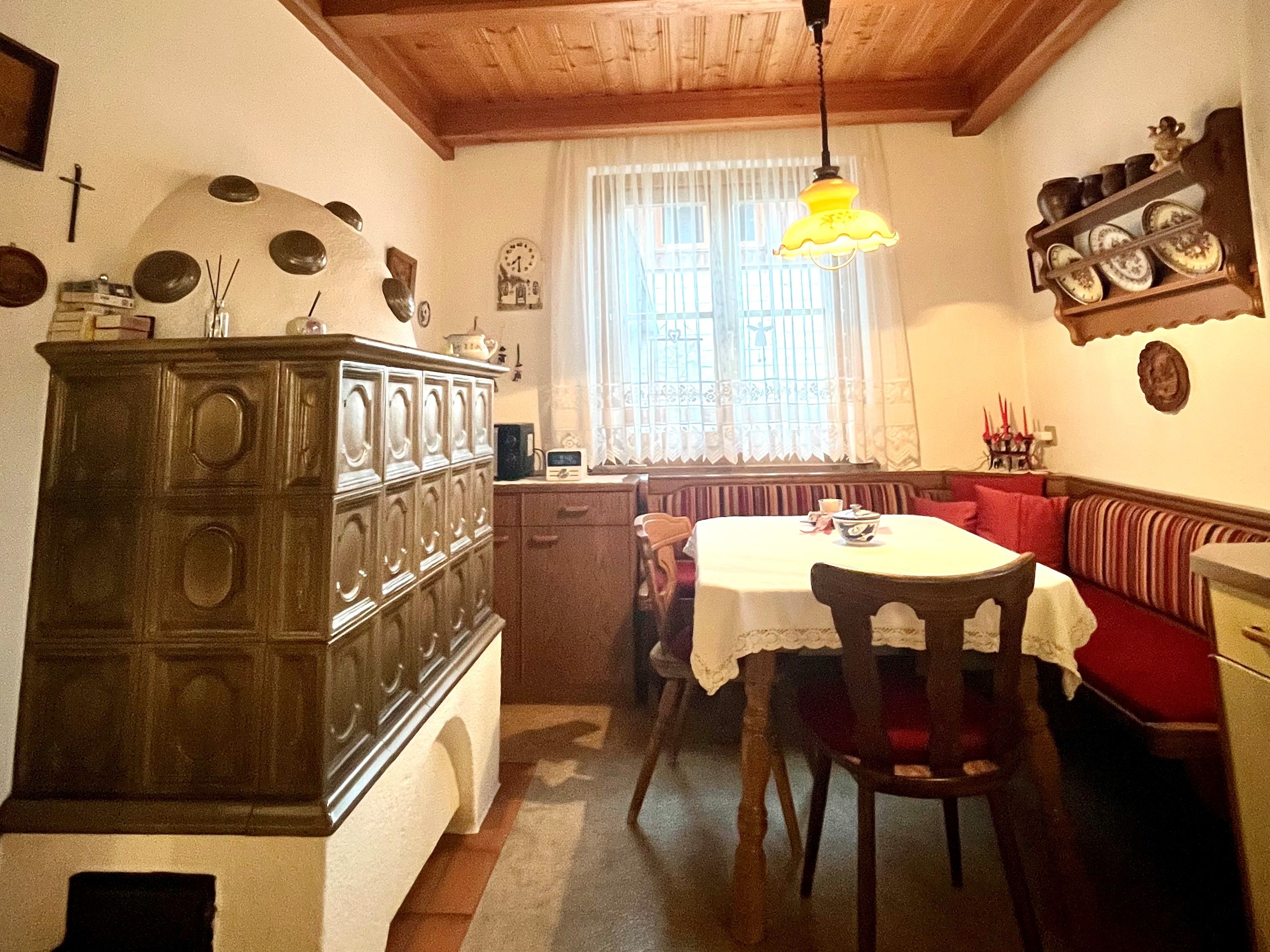 Hangulatos konyha cserépkályhával, fa asztallal és sarokpaddal.