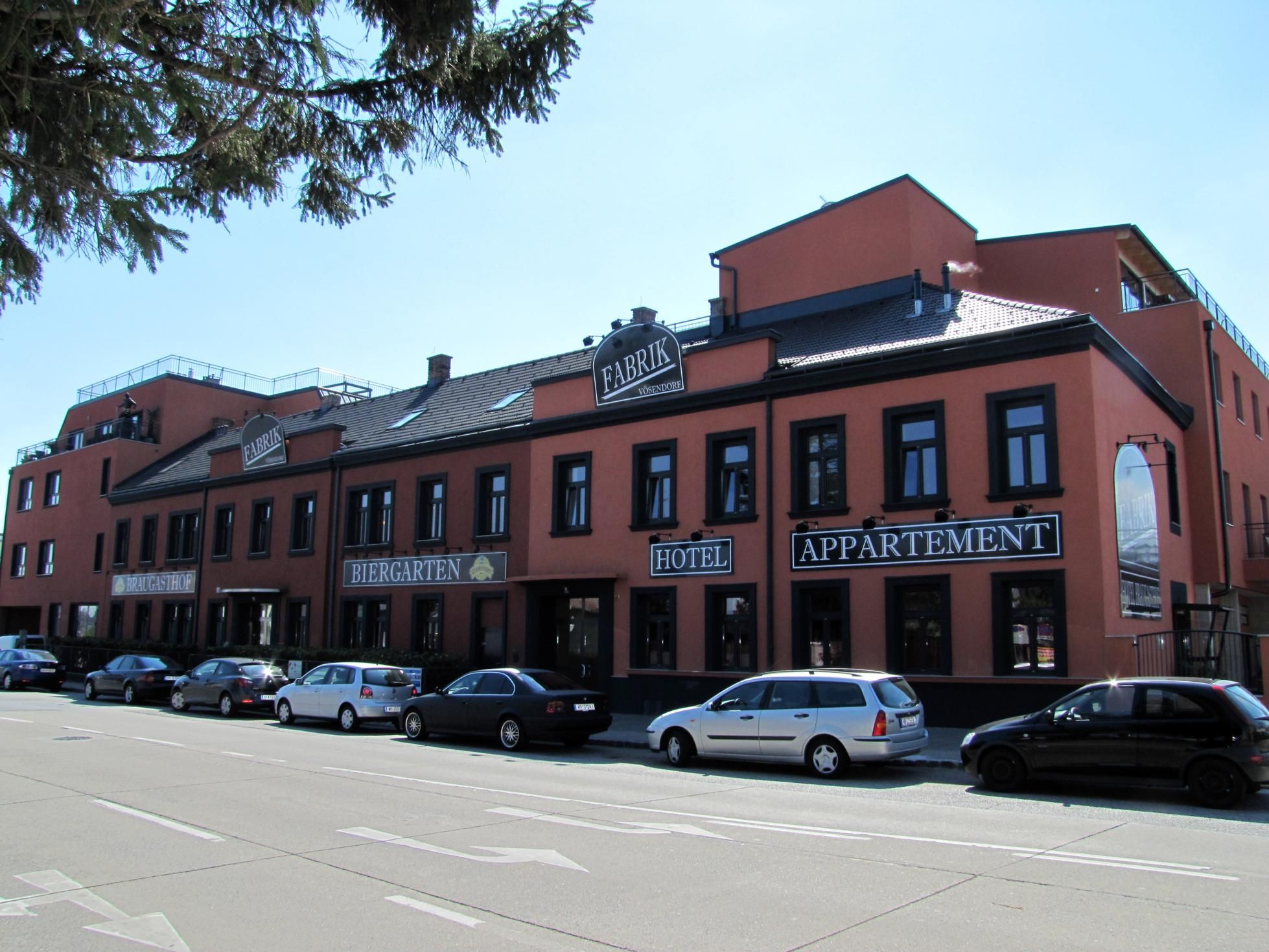 A Hotel Braugasthof Fabrik külső nézete, előtte parkoló autókkal.