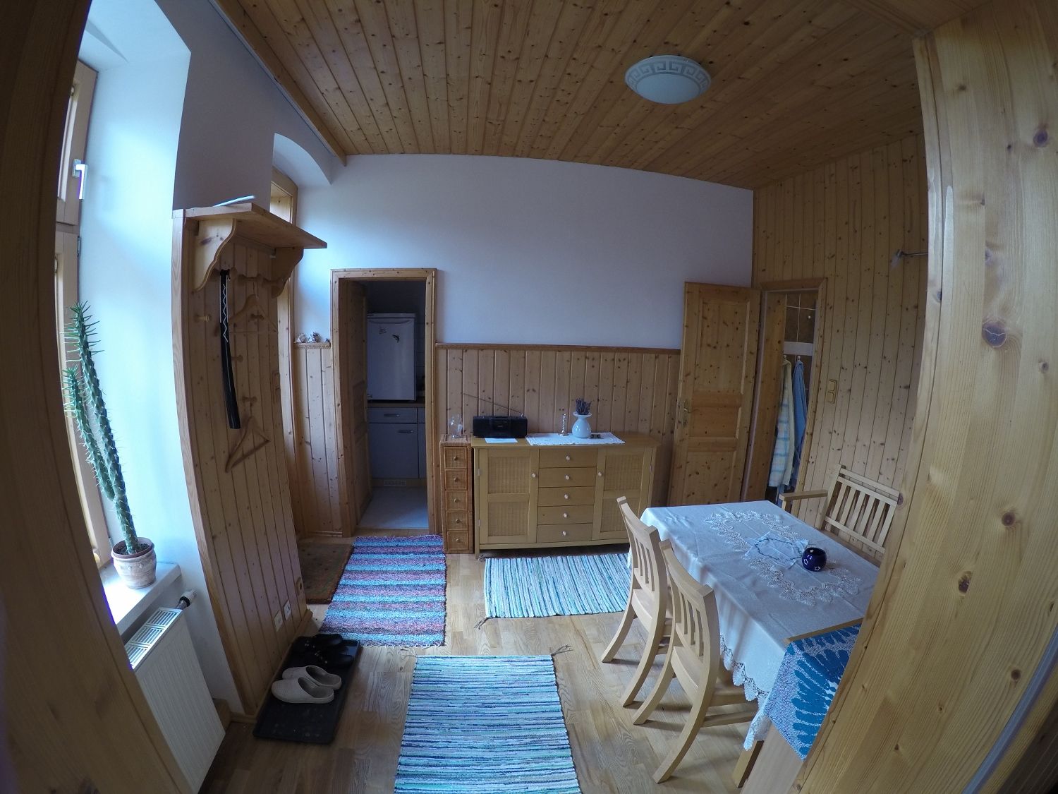 Ebédlő egy nyaraló apartmanban, fából készült falakkal, étkezőasztallal, székekkel és szőnyegekkel.