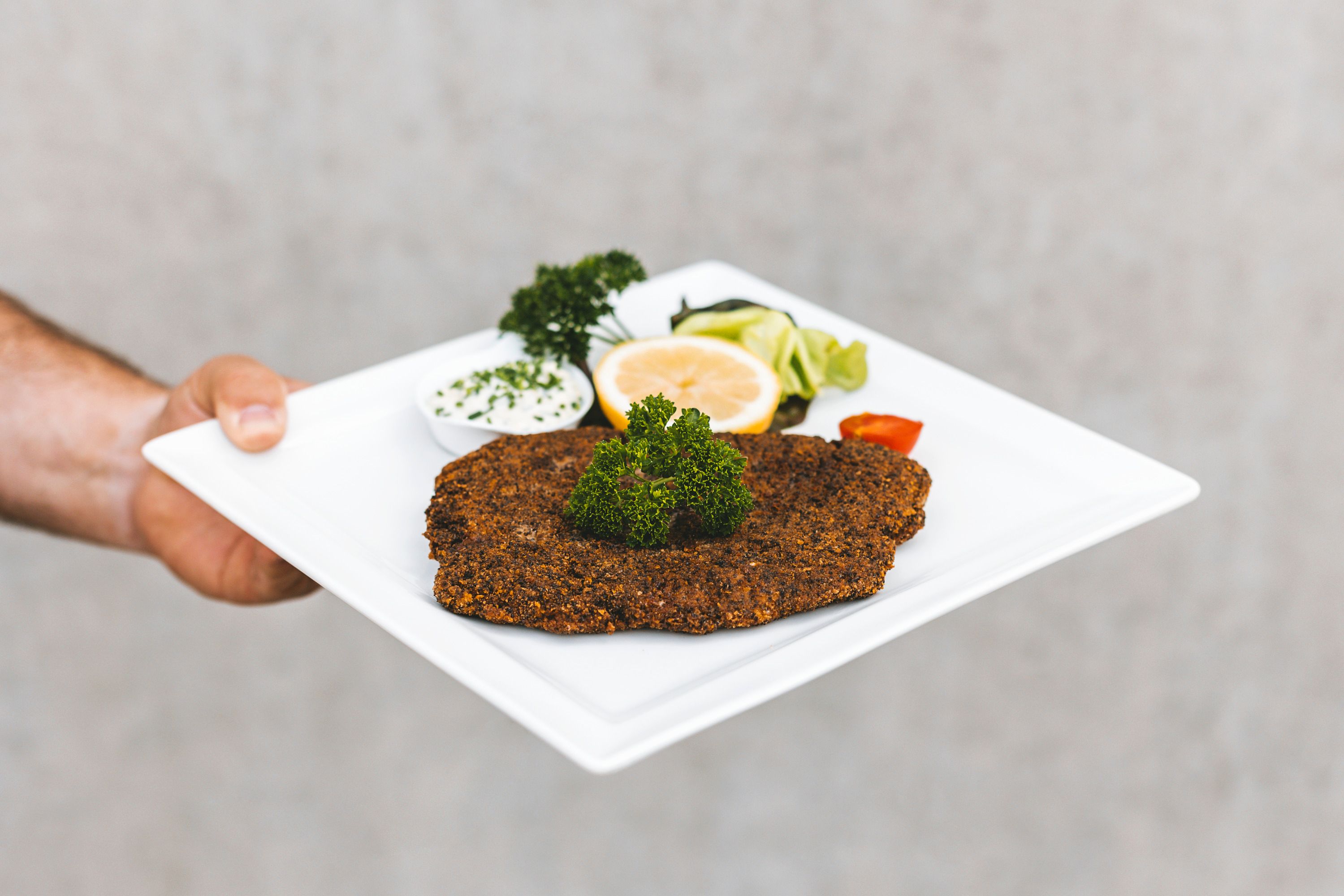 Egy tányér rántott hallal, citrommal, petrezselyemmel és mártással.