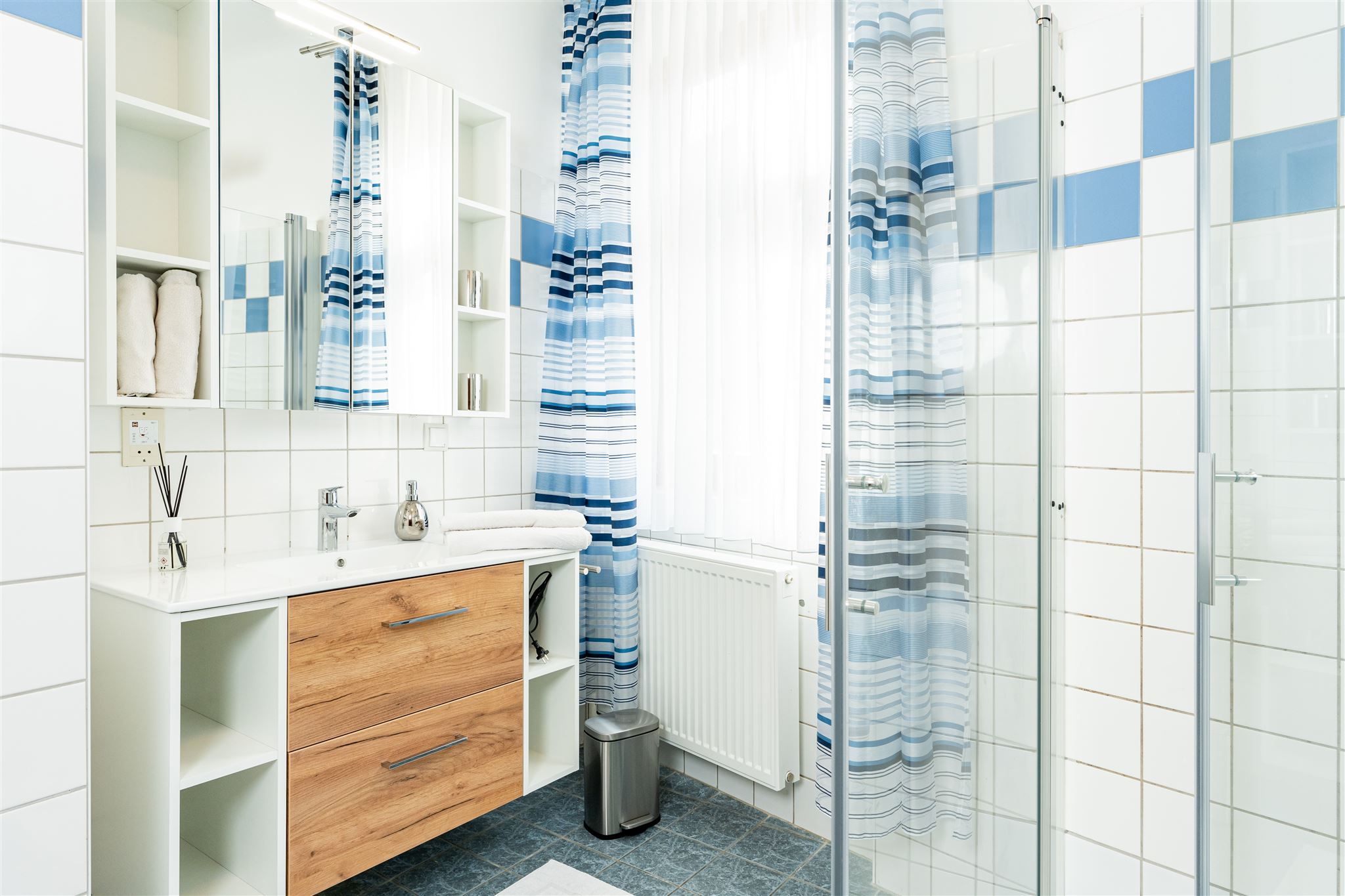 Modern fürdőszoba fából készült szekrénnyel, tükörrel, zuhanyfüggönnyel és csempével.