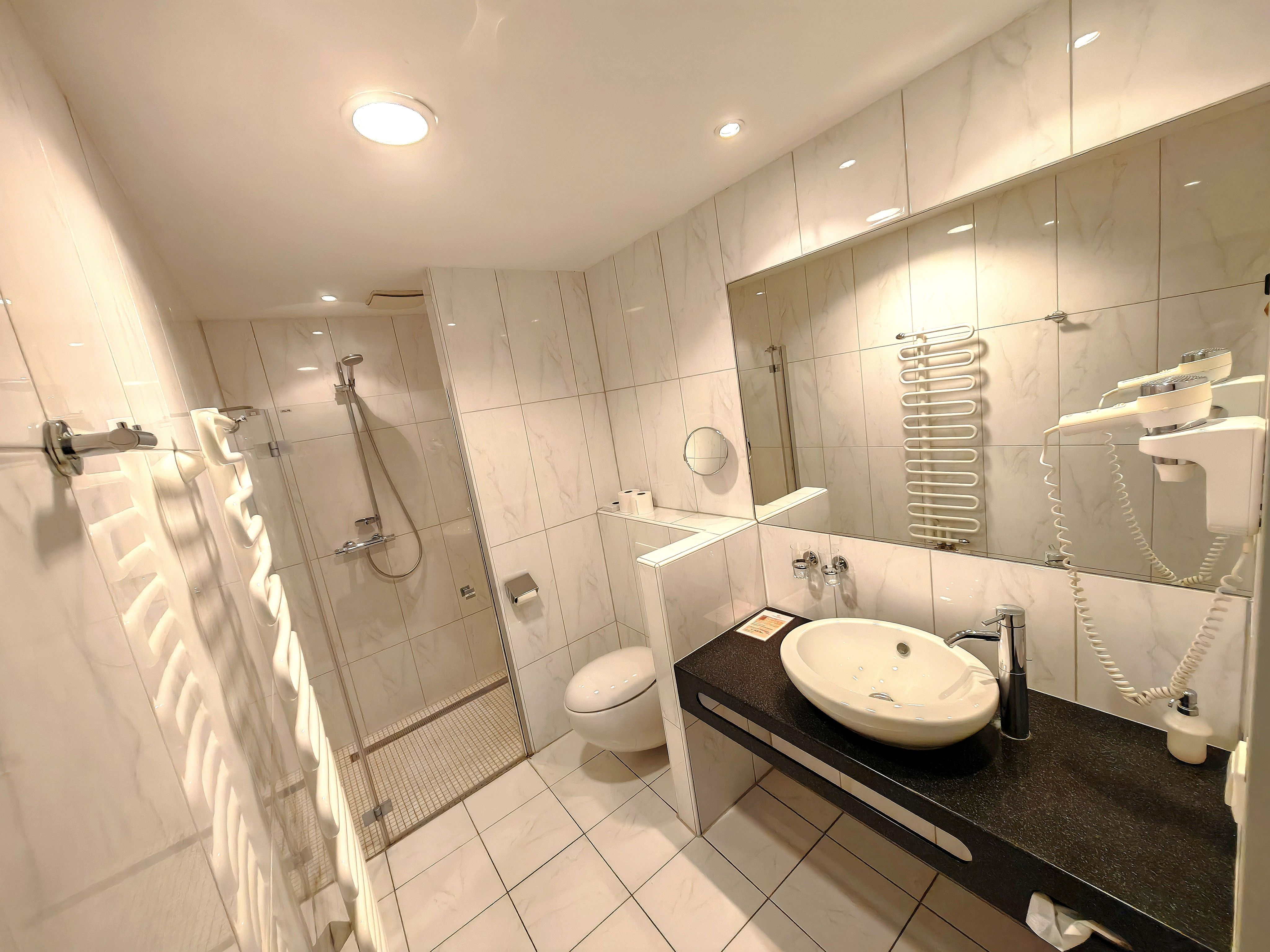 Modern fürdőszoba zuhanyzóval, mosdóval és WC-vel.