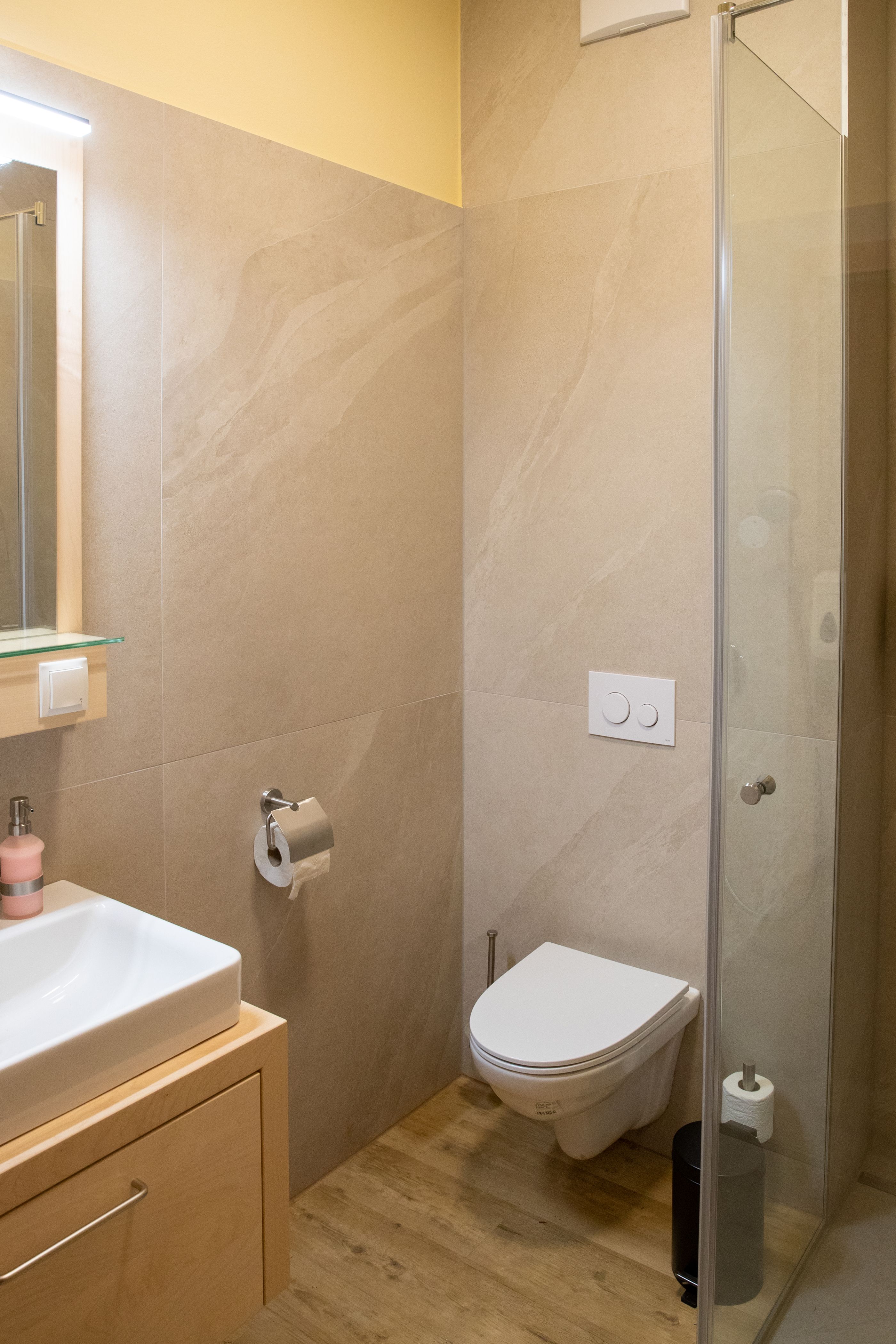 Modern fürdőszoba mosdóval, WC-vel és zuhanyfülkével.
