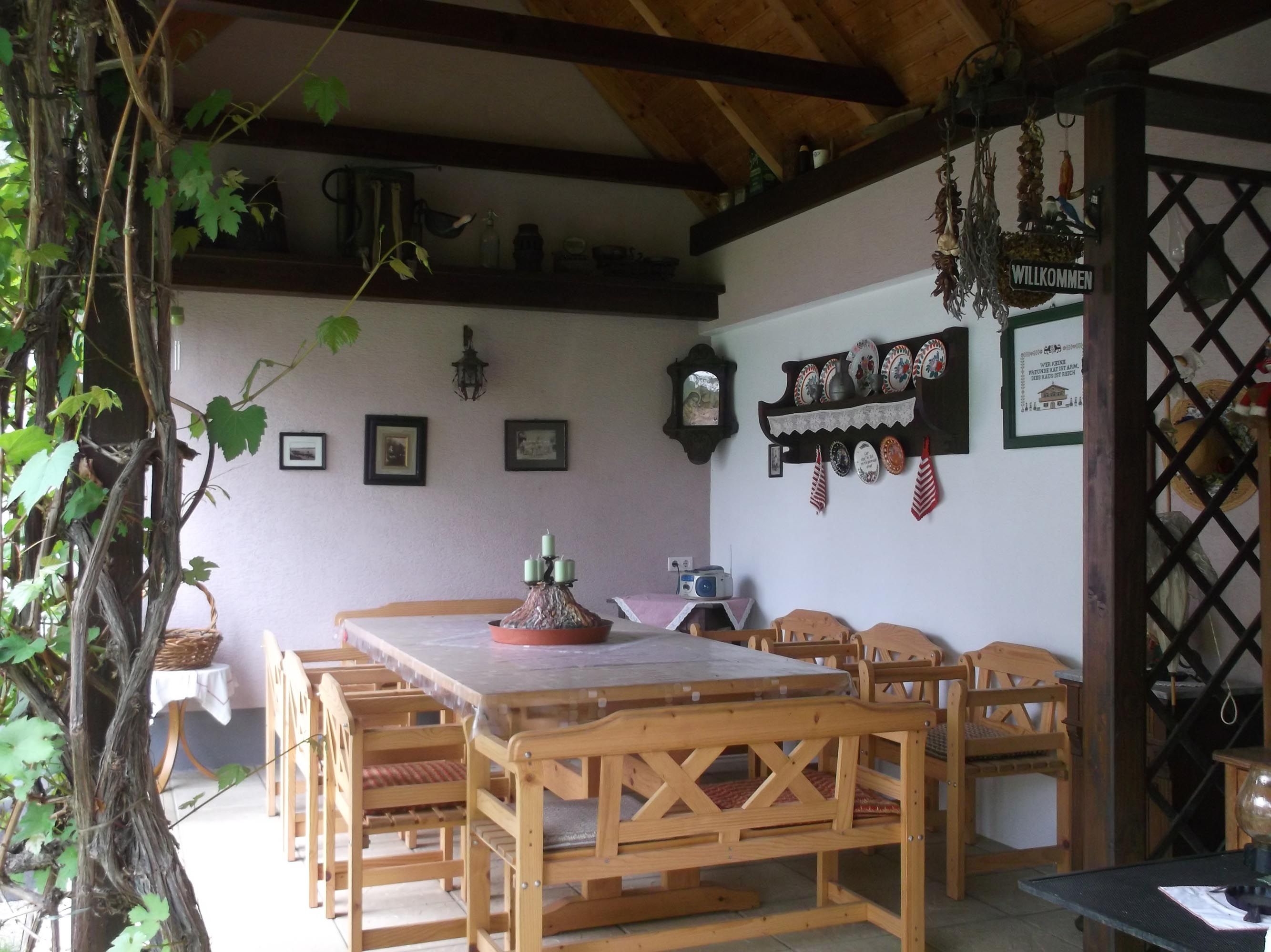 Fedett terasz asztallal és székekkel, a háttérben egy fal különböző faldíszekkel.