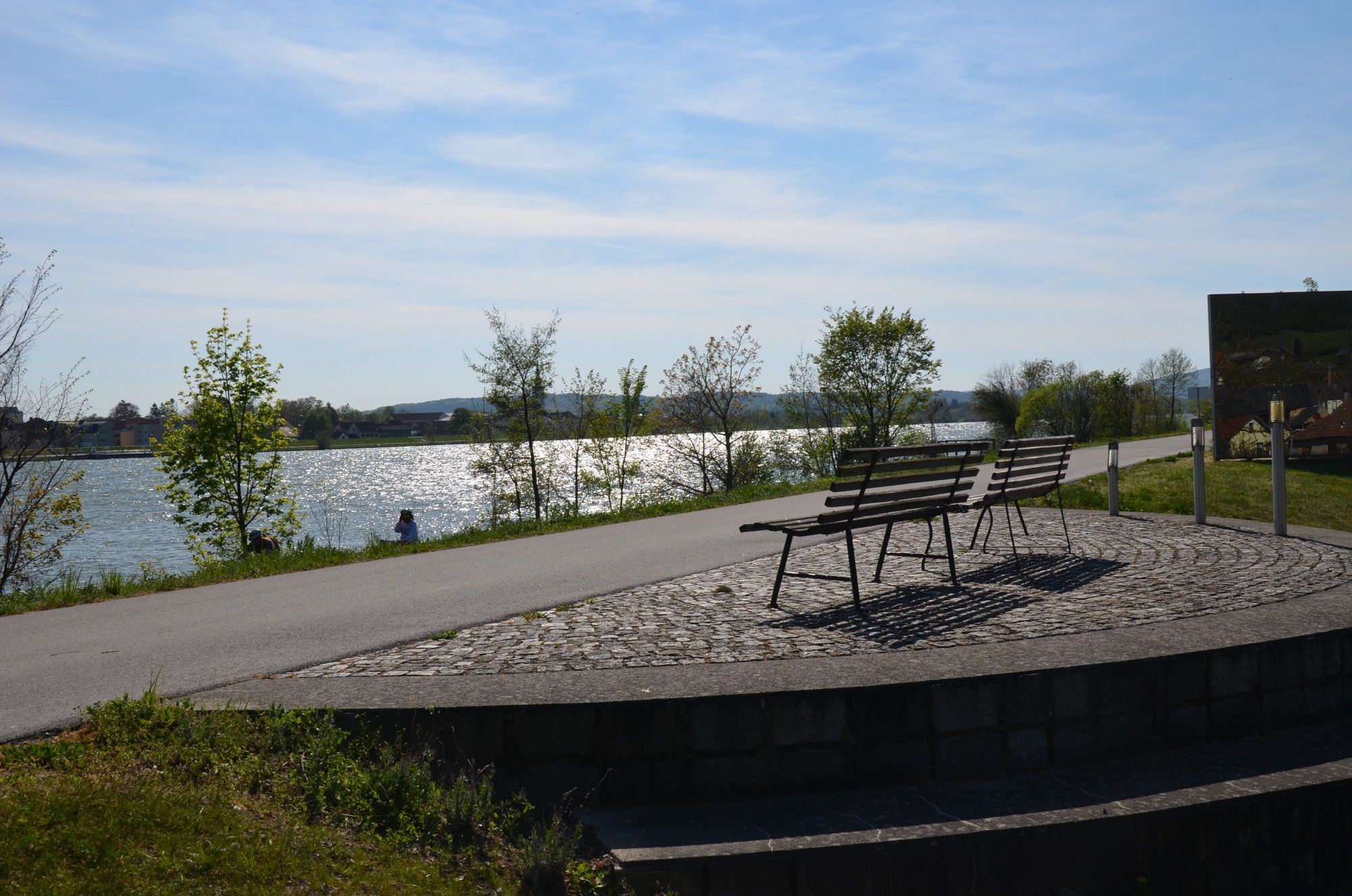 Két pad a folyóra néző kilátással napsütéses időben.