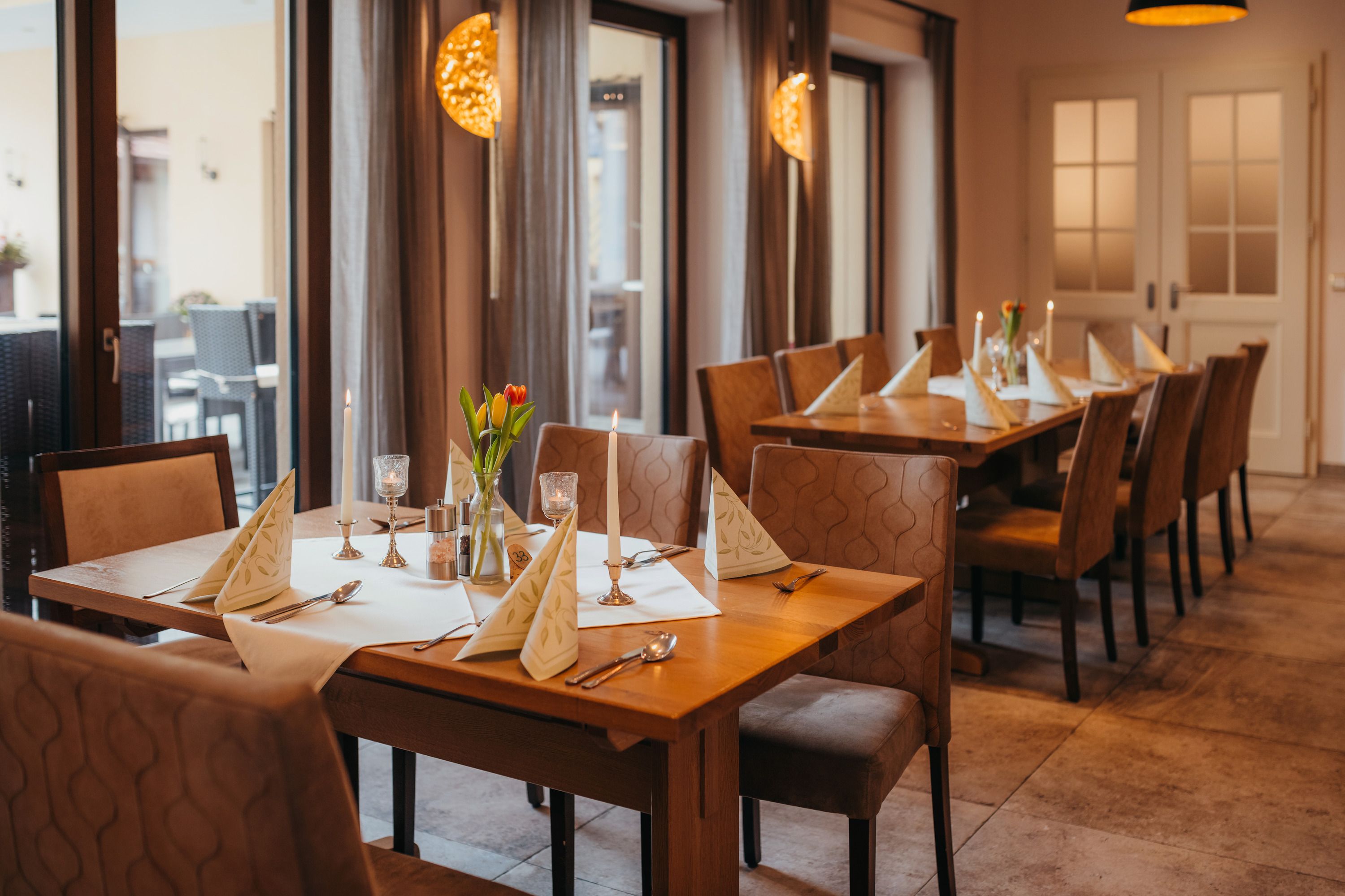 Egy hangulatos asztal egy kocsmában, gyertyákkal és virágokkal.