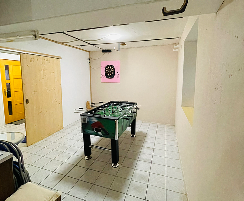 Egy játékszoba egy asztali fociasztallal és egy darts táblával a falon.