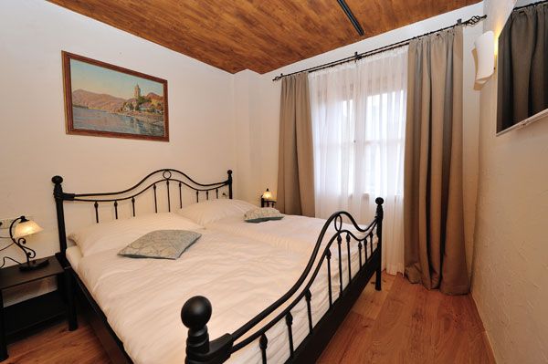 Hálószoba fém ággyal, fapadlóval és festéssel a falon.