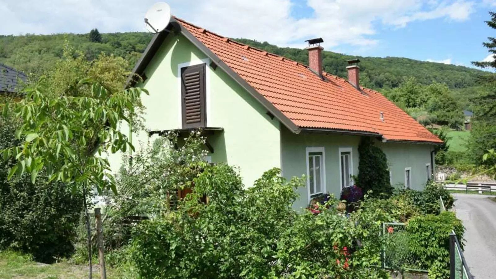 Zöld családi ház kívülről piros tetővel