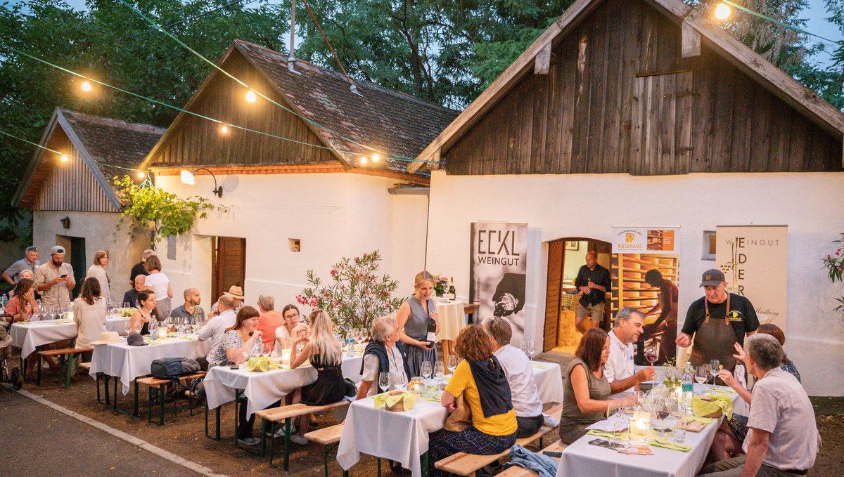 Az emberek asztaloknál ülnek egy borászat előtt a Pincesoron.