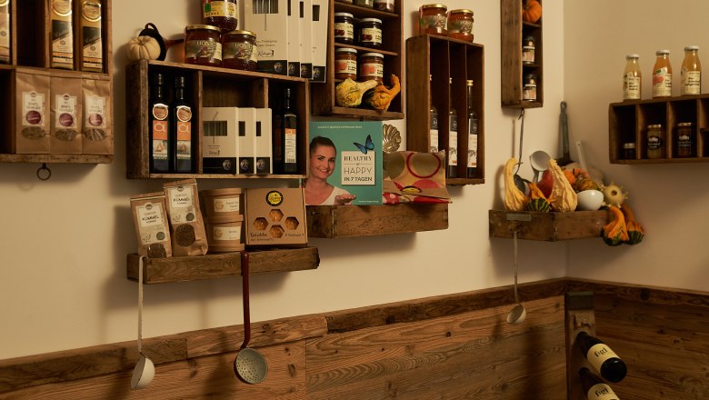 Regale mit Lebensmitteln und Kochutensilien an einer Holzwand.