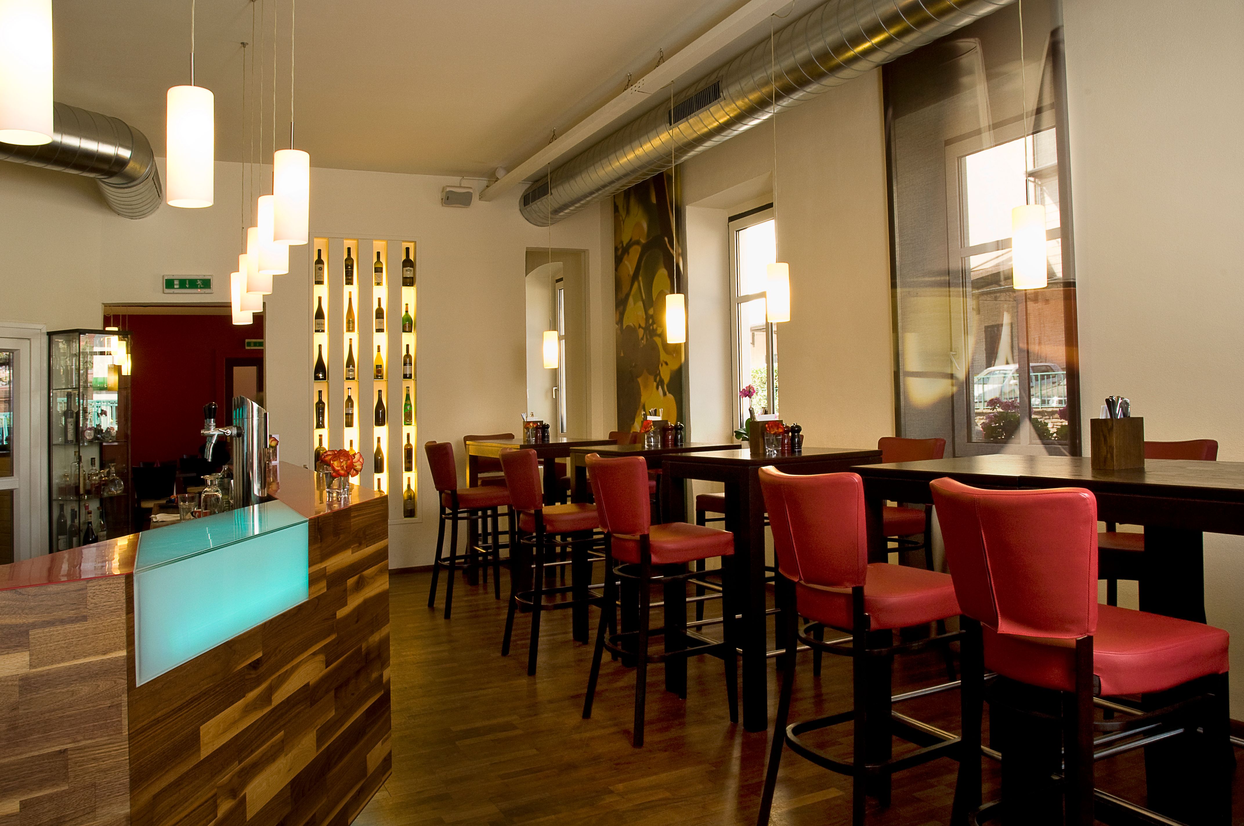 Belső nézet egy modern étteremről, piros székekkel és fapulttal.