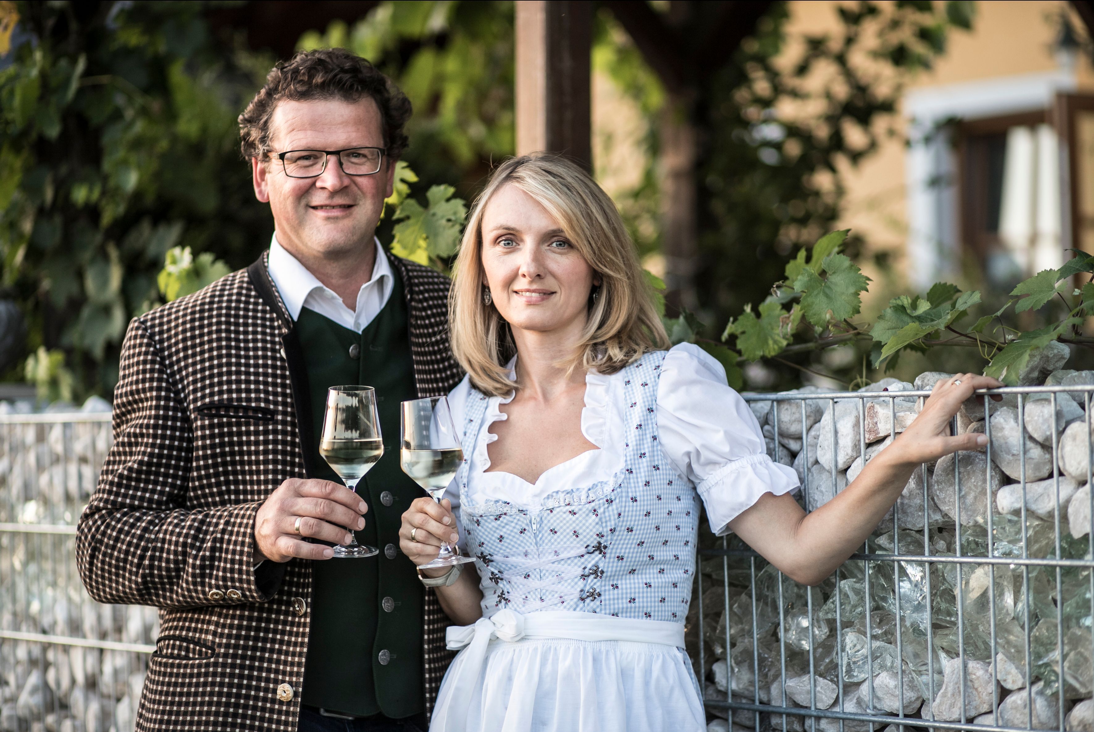 Egy férfi és egy nő hagyományos öltözékben borospoharat tart a kezében.