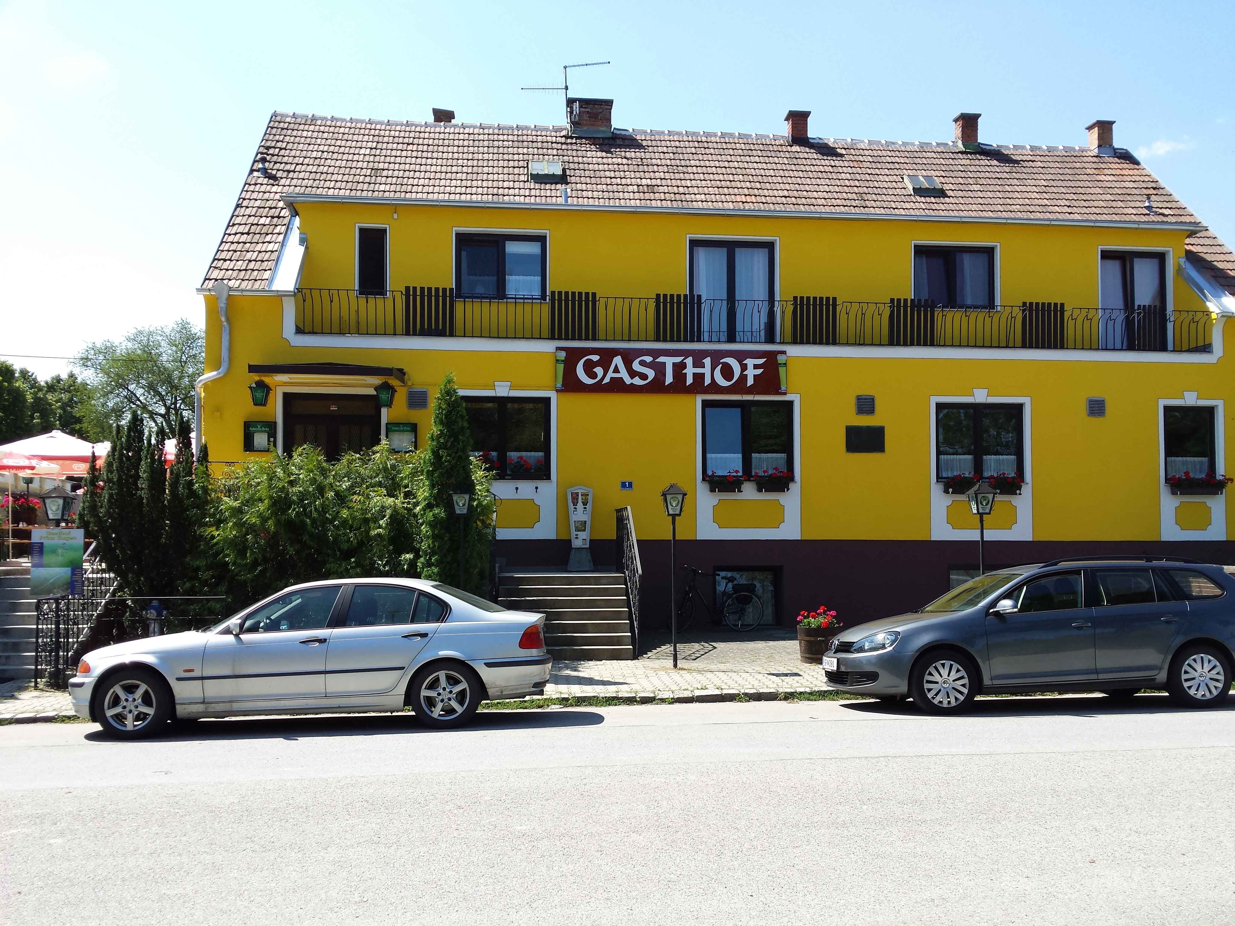 "Gasthof" feliratú sárga épület, előtte két autó parkol.