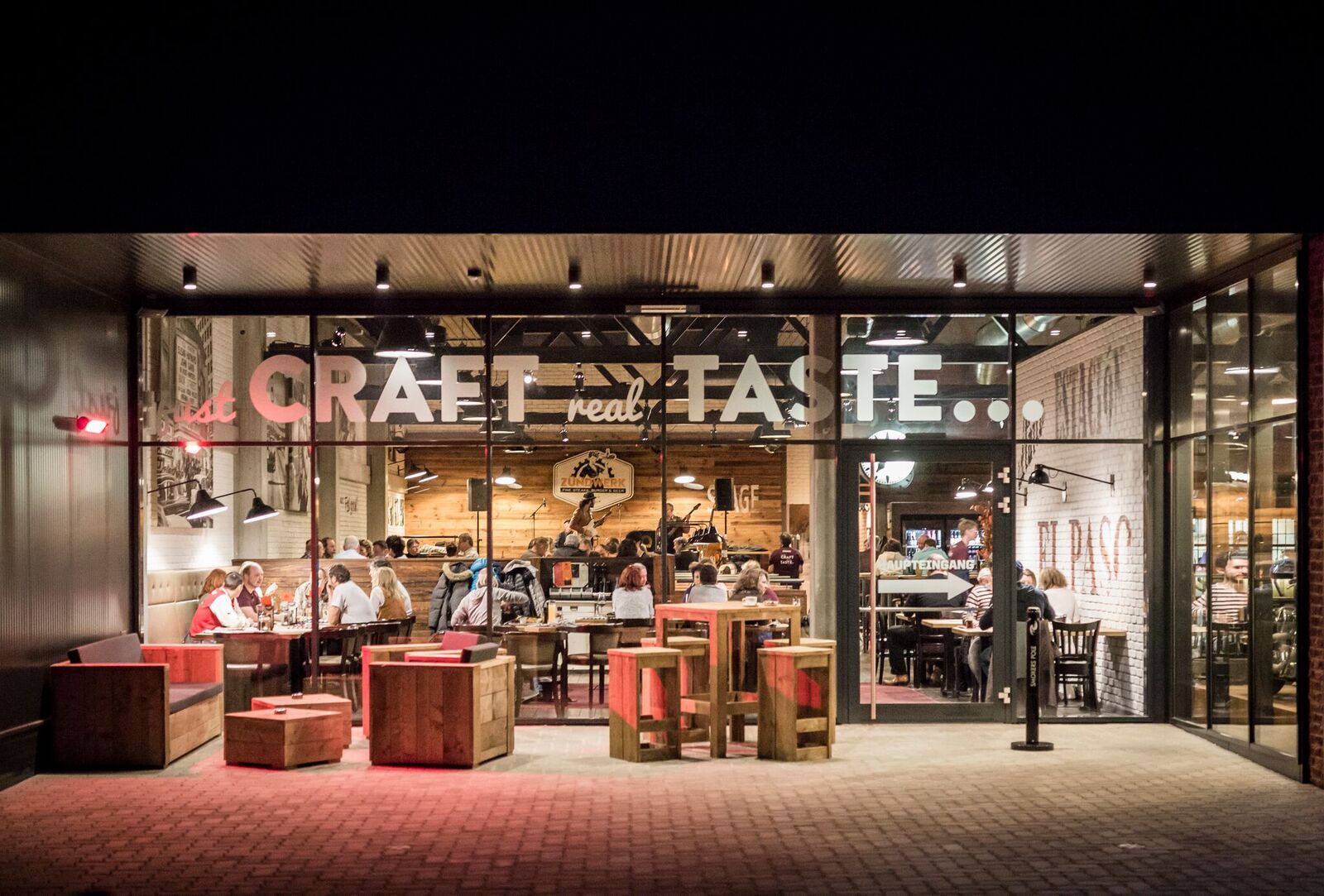 Egy étterem külső nézete üvegfronton, belül emberek ülnek az asztaloknál.