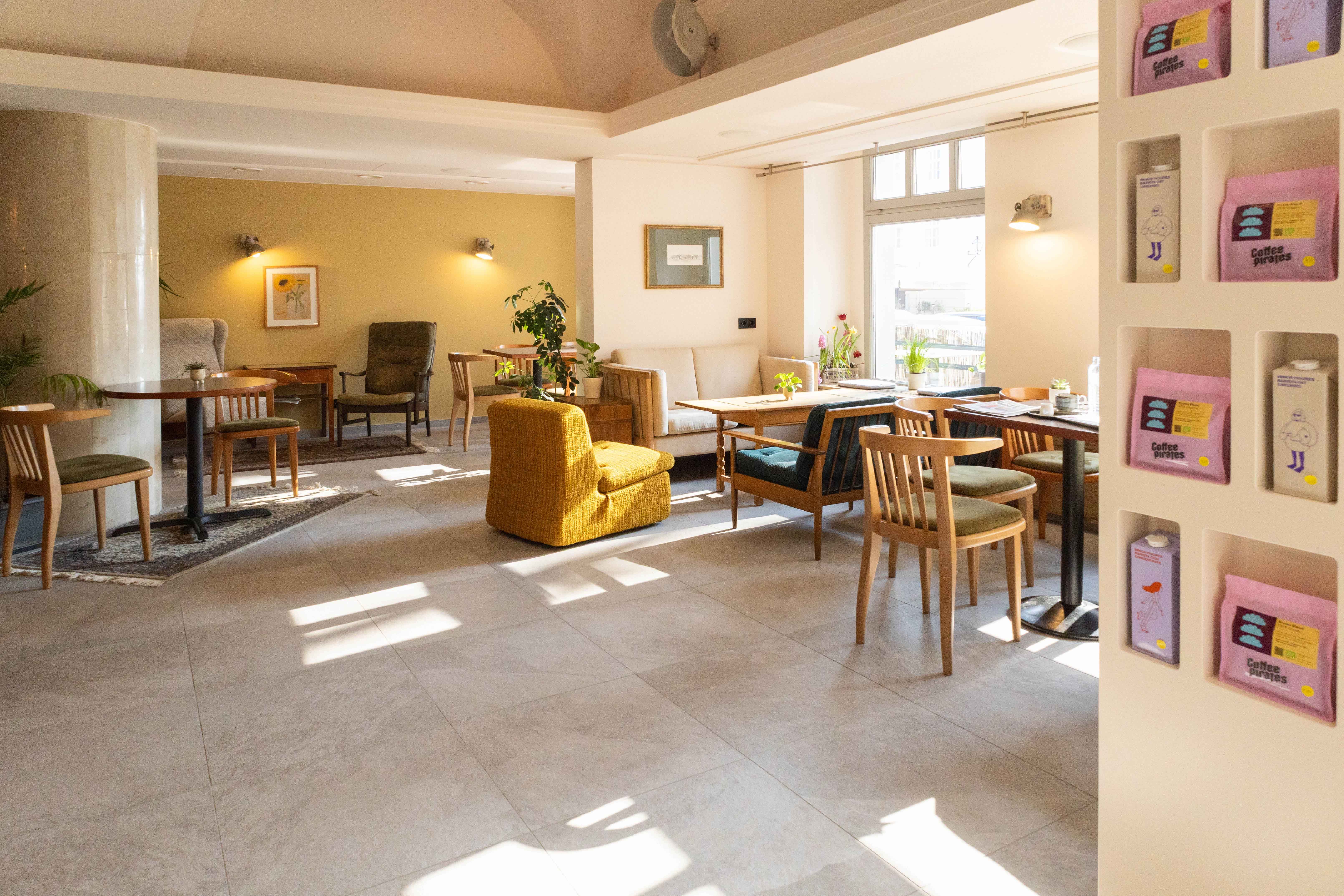 Egy hangulatos kávézó belső nézete, fából készült bútorokkal és növényekkel.