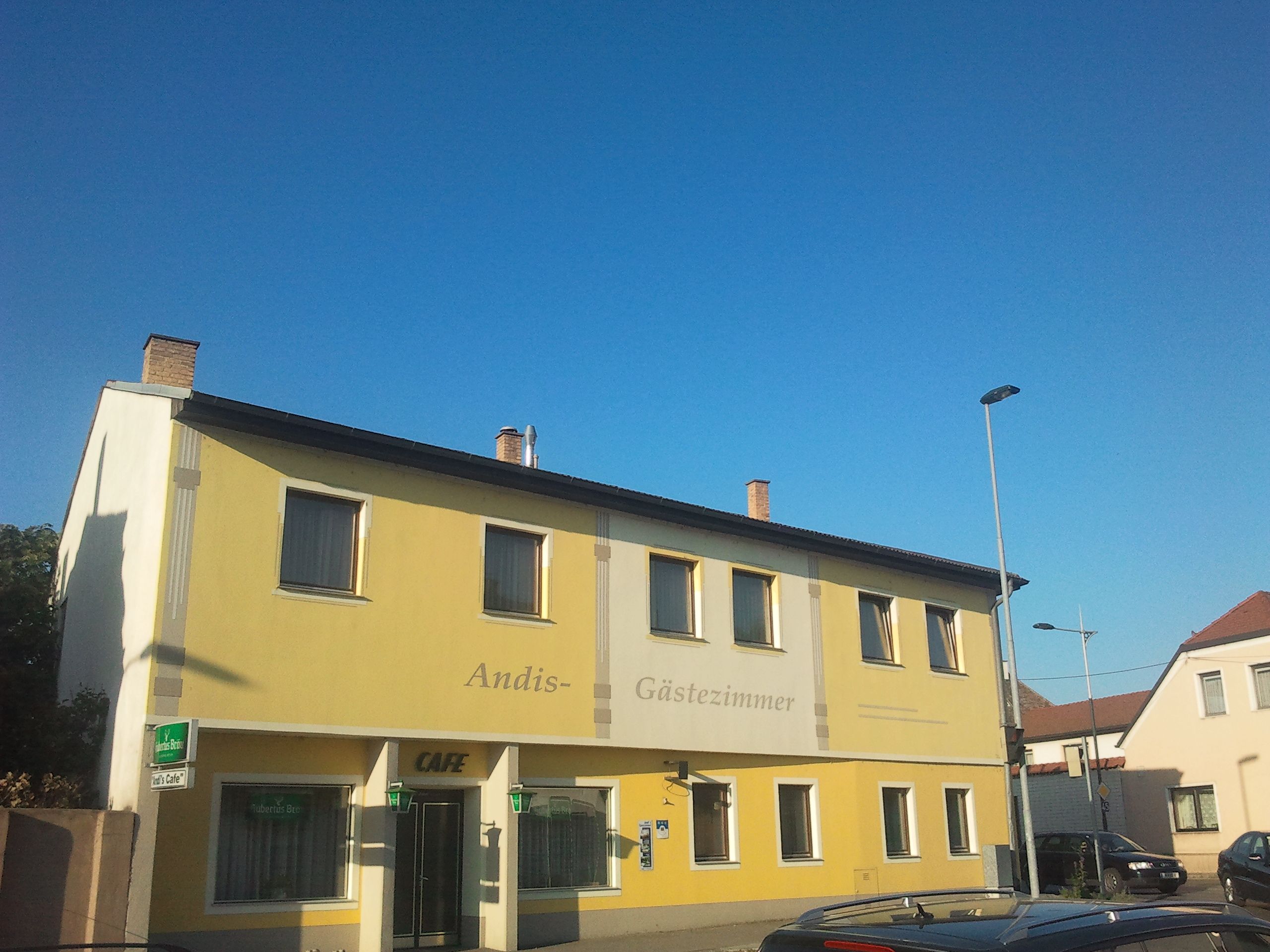 Sárga színű épület 'Andis Gästezimmer' és 'Cafe' felirattal.