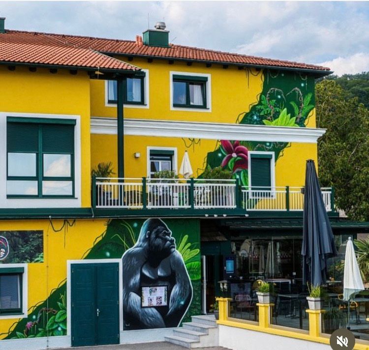 Sárga épület gorilla falfestményekkel és dzsungelmotívumokkal.
